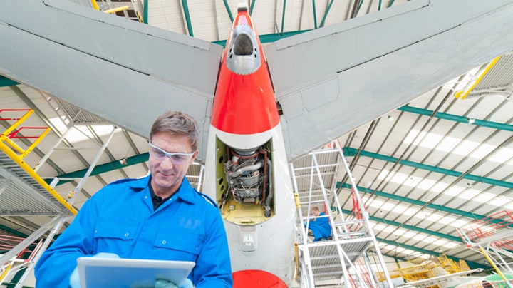 A man works on the tail section of an airplane