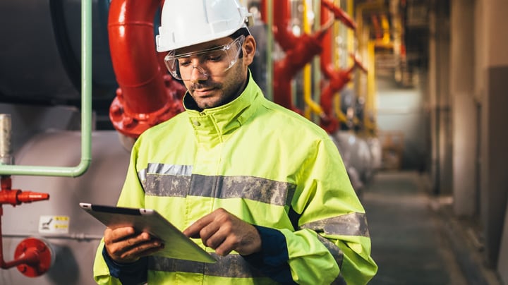 Man checking tablet at oil and gas plant